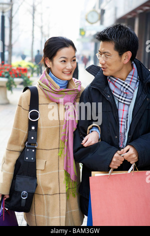 Young Couple Holding shopping bags, Smiling at each other Banque D'Images