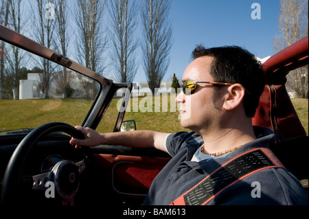 Homme conduisant une voiture de sport MG Midget classique convertible avec le toit vers le bas sous le soleil d'été Banque D'Images