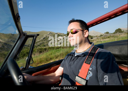 Homme conduisant une voiture de sport MG Midget classique convertible avec le toit vers le bas sous le soleil d'été Banque D'Images