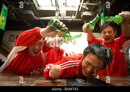 Verser l'alcool sur les jeunes hommes Young Man Leaning On Bar Banque D'Images