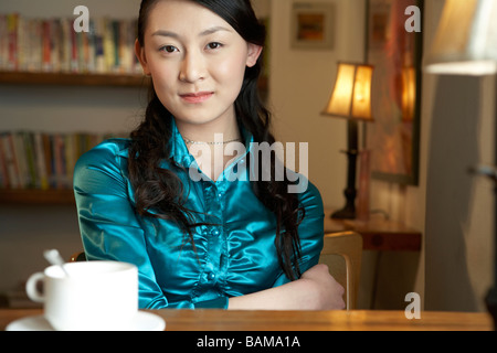 Femme assise à une table avec une tasse à café Banque D'Images