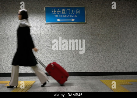 Les femmes tirant une valise rouge dans la borne du Métro Banque D'Images