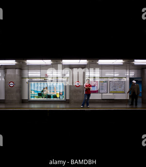 Deux personnes debout sur la plate-forme à la station de métro Embankment à Londres. Photo par Gordon 1928 Banque D'Images