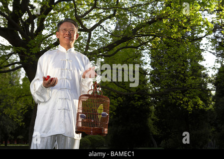 Habillé traditionnellement chinois avec Zen balles et un oiseau en cage Banque D'Images