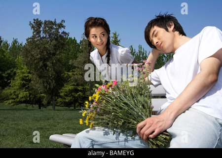 L'homme et la femme dans un parc holding Flowers Banque D'Images