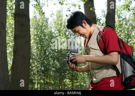 Jeune homme regardant à travers son appareil photo Smiling Banque D'Images