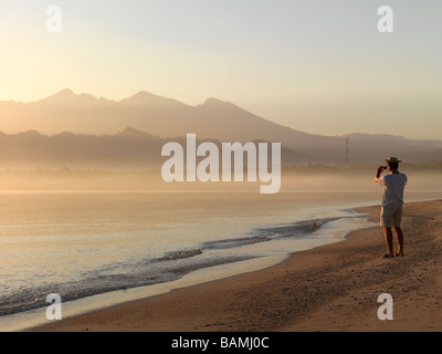 Un homme prend une photo du soleil levant sur la mer de Java à Lombok en Indonésie. Banque D'Images