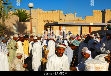 Les hommes habillés en costume traditionnel omanais le Dishdasha chèvre sur la place du marché, Nizwa, Sultanat d'Oman Banque D'Images