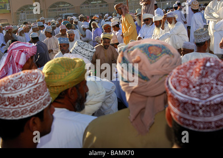 Les hommes habillés en costume traditionnel omanais le Dishdasha et le kummah sur le marché de chèvre, Nizwa, Sultanat d'Oman Banque D'Images