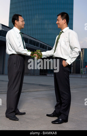 Deux Businessmen Shaking Hands enveloppé de lierre Banque D'Images