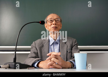 Teacher Sitting At Desk et de parler dans un microphone Banque D'Images