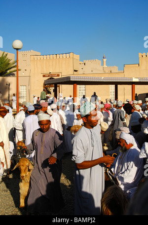 Les hommes habillés en costume traditionnel omanais le Dishdasha chèvre sur la place du marché, Nizwa, Sultanat d'Oman Banque D'Images