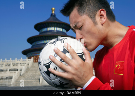 Jeune joueur de soccer masculin Soccer Ball baiser en face de Temple Banque D'Images