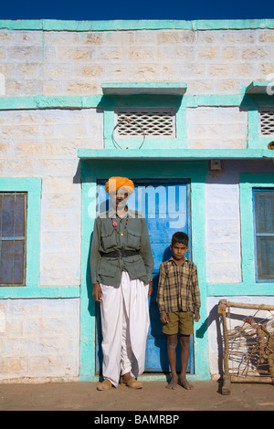 L'homme et garçon debout à l'extérieur d'une maison peinte en couleurs près de Osian, Rajasthan, Inde Banque D'Images