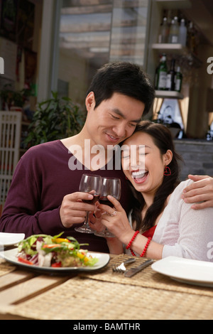 Jeune couple faire un toast lors d'un repas Banque D'Images