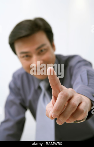 Businessman Pointing at Camera, Smiling Banque D'Images