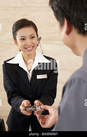 Transaction entre jeune homme et femme dans le hall de l'hôtel Banque D'Images
