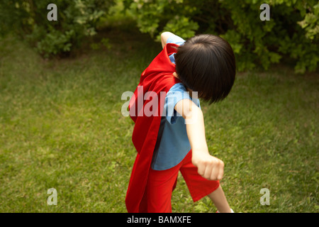 Boy in Cape Rouge Playing In Garden Banque D'Images