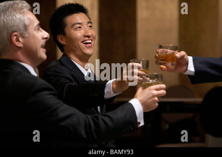 Trois chefs d'entreprise partagent un toast à un club d'affaires exclusif Banque D'Images
