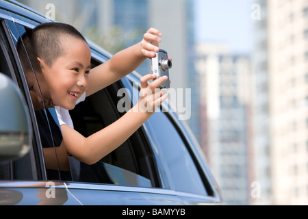 Young boy leaning out car window Banque D'Images