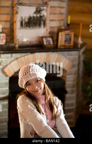 Young woman smiling devant une cheminée Banque D'Images