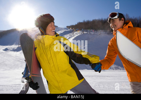 Jeune homme avec un snowboard tenant la main à une jeune femme Banque D'Images