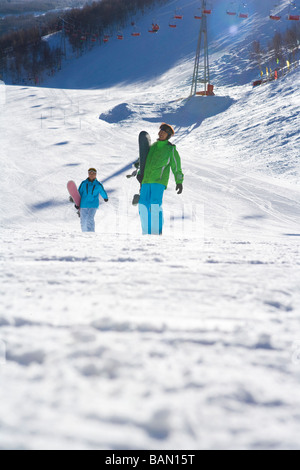 Les jeunes avec des snowboards walking through snowy landscape Banque D'Images