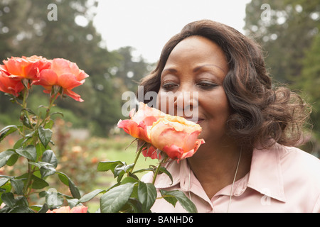 Middle-aged African woman smelling roses à l'extérieur Banque D'Images