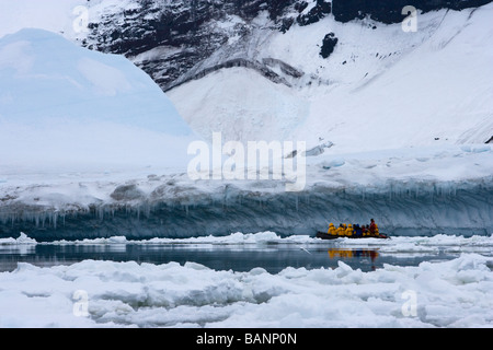 Les écotouristes aventure explorer grand bleu iceberg sur zodiac expédition excursion de croisière croisière à l'Île à distance Peter JE L'ANTARCTIQUE Mer Bellinghausen Banque D'Images