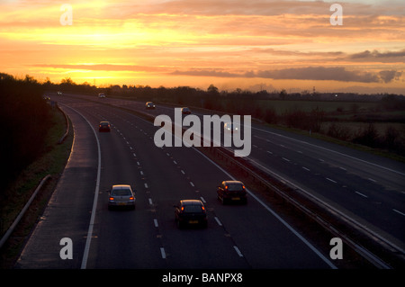 La circulation routière sur l'autoroute M5 au coucher du soleil, près de Dursley, Gloucestershire. Banque D'Images