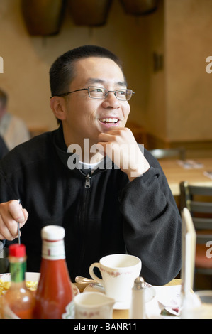 Asian man eating in restaurant Banque D'Images