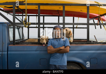 Hispanic man with dog leaning against truck Banque D'Images