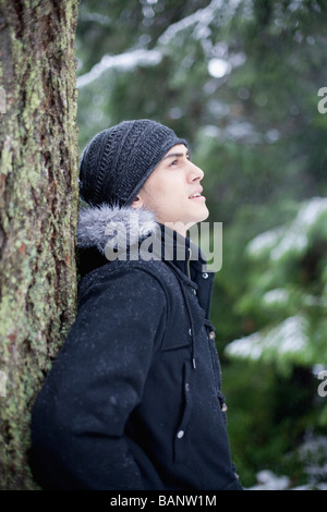 Mixed Race man leaning against tree trunk Banque D'Images