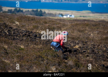 Scottish Woman Cutting & Harvesting de tourbe pour le carburant. A Peat Harvester in peatland fields, Isle of Sky, Écosse, Royaume-Uni Banque D'Images