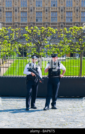 La place du parlement de Westminster , , deux policiers en uniforme métropolitaine armés montent la garde à l'extérieur de Soleil Chambre des communes Banque D'Images