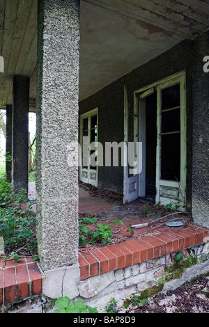 Une maison abandonnée se trouve en mauvais état dans le pays avec des plantes qui poussent à travers les fissures Banque D'Images