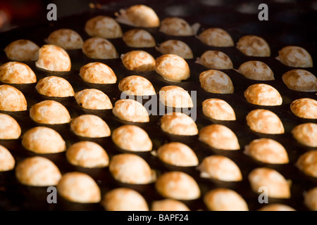 Les aliments traditionnels en Hollande. Petites crêpes poffertjes, néerlandais, sur un plaque de cuisson en fonte à Amsterdam. Banque D'Images