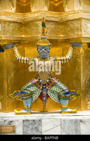 Close up d'un des démons mythologiques soutenant un grand chedi doré ou Stupa à Wat Phra Kaew, Bangkok, Thaïlande Banque D'Images
