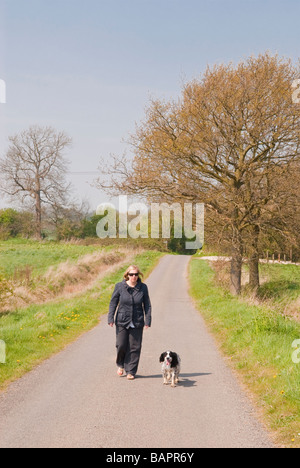 Une femme promener son chien seul le long d'un chemin de campagne du Suffolk, Royaume-Uni Banque D'Images