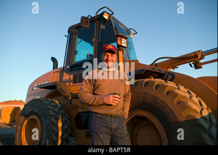 Tôt le matin, portrait de propriétaire de petite entreprise et de l'opérateur du chargeur avant sur un site de construction Banque D'Images