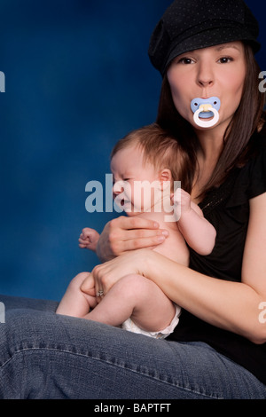 La jeune femme tenant sur ses genoux avec sucette dans sa bouche Banque D'Images