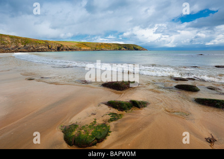 Rocky Bay , Co.Cork, République d'Irlande à marée basse, montrant le ciel bleu , le sable et rochers au premier plan Banque D'Images