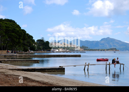 Paysage de la baie de Pollensa et de pin à pied avec un jeune couple sur un quai en bois contre les montagnes et ciel bleu Banque D'Images