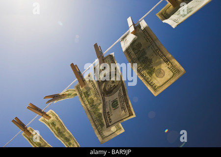 Blanchiment de capitaux - Dollars : 100 $ dollar bills le séchage dans le vent sous un ciel bleu profond avec des reflets intentionnelle. Banque D'Images