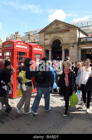 Des foules de touristes et de shopping et quelques boîtes de téléphone rouge passé au soleil à l'extérieur du marché de Covent Garden à Londres. Banque D'Images