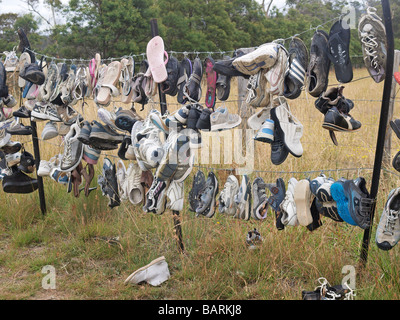 Formateurs perdus et abandonnés, des tongs et des chaussures accrochées sur barbelés Tasmanie Australie Banque D'Images