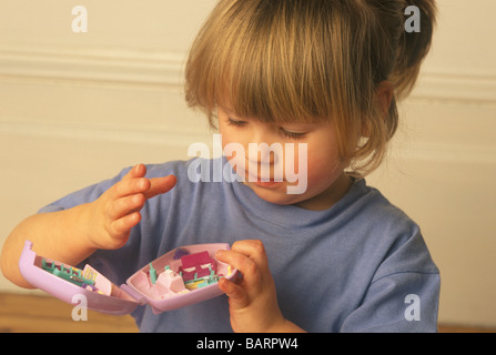 Petite fille jouant avec des jouets miniatures Polly Pocket Banque D'Images