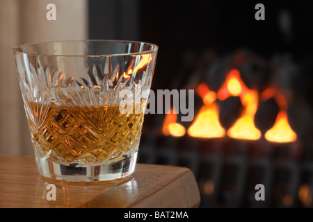 Petit Verre de single malt scotch whisky dans un verre à whisky en cristal sur une table par une cheminée Angleterre Royaume-uni Grande-Bretagne Banque D'Images