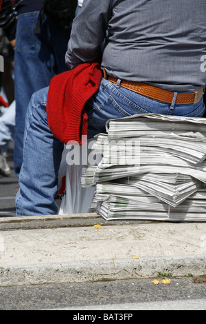 Homme assis sur une pile de journaux de rue dans la ville de la ville Banque D'Images