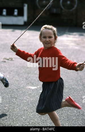 Fille de l'école primaire en sautant dans l'aire de jeux Banque D'Images